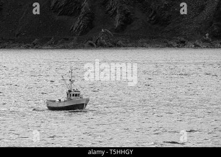 Photo en noir et blanc d'Un petit bateau de pêche commercial norvégien en route, À quelques kilomètres à l'ouest de Honningsvåg, au-dessus du cercle polaire arctique en Norvège. Banque D'Images