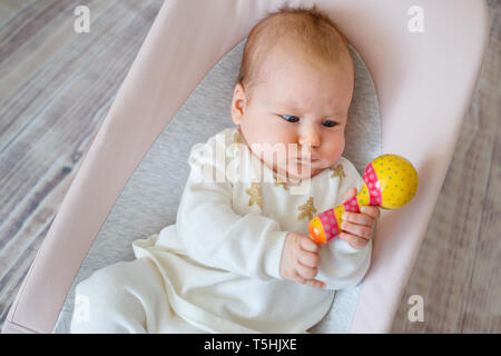 Adorable baby girl in videur. Toddler Playing with toy hochet coloré à l'intérieur. Activités pour enfants Banque D'Images