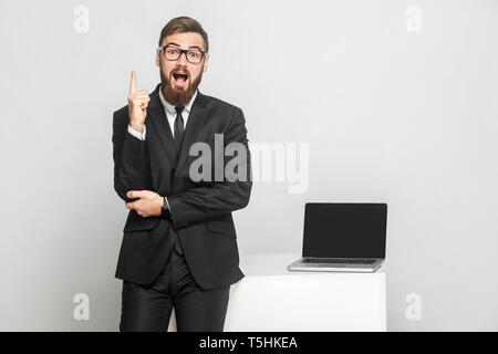 Nouvelle idée ! Portrait of handsome surpris bearded businessman sont debout près de son lieu de travail et montrant doigt vers le haut avec mo Banque D'Images