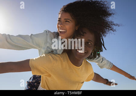 Young man giving woman piggyback at beach Banque D'Images