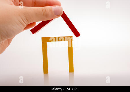 Hand holding pièces domino formant une forme de maison Banque D'Images