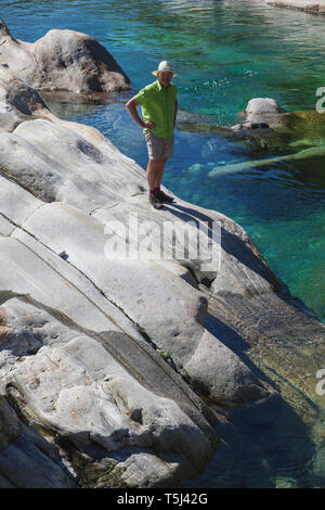 La Suisse, la vallée de Verzasca, Tessin, l'homme debout sur la roche à effacer les eaux turquoise de la rivière Verzasca Banque D'Images