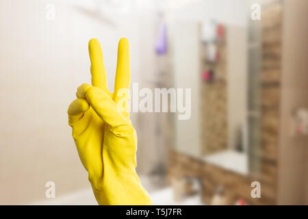 Libre de la personne faisant la paix ou la victoire avec les doigts portant des gants en latex jaune Banque D'Images