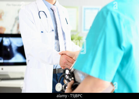 Deux médecins dans office shaking hands célébrant la réussite du traitement Banque D'Images