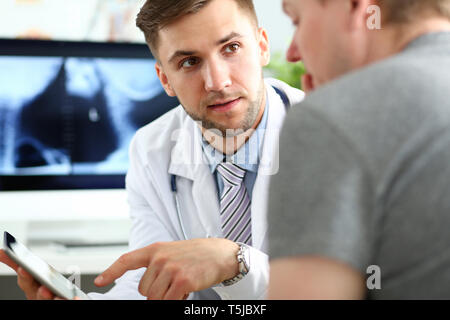 Beau mâle médecin patient consultation montrant quelque chose à l'écran du PC tablette Banque D'Images