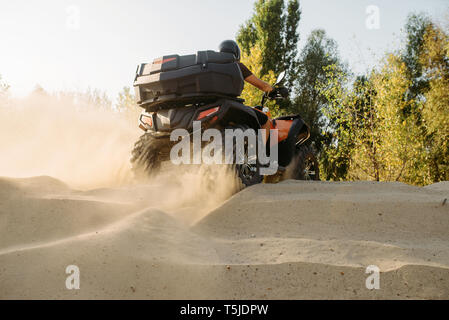 Vtt dans la carrière de sable, nuages de poussière. Conducteur en casque sur quad, extreme freeride sur quadbike en désert de dunes Banque D'Images