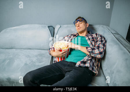 Spectateur mâle avec le pop-corn de dormir sur un canapé dans la salle de cinéma avant la chaîne Showtime. Homme de cinéma, un style de vie de divertissement Banque D'Images