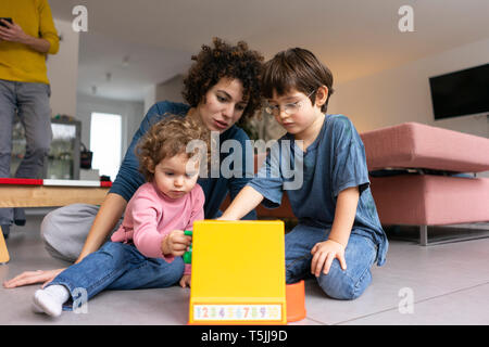 Lecture de la mère et des enfants en train de jouer avec un jouet jusqu'à Banque D'Images