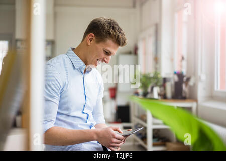 Smiling young businessman using tablet in office Banque D'Images