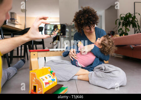 Mère et fille jouer dans la salle de séjour, la prise de photos smartphone fater Banque D'Images