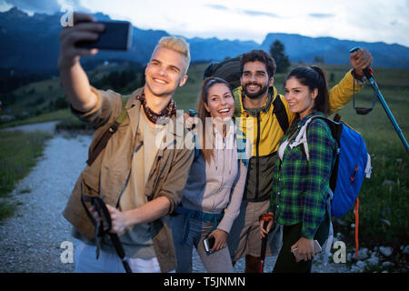 Groupe d'amis se reposant sur une montagne lors d'une randonnée. Les randonneurs selfies se détendre et de prendre. Banque D'Images