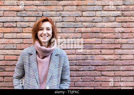 Portrait of a young woman standing à un mur de briques Banque D'Images
