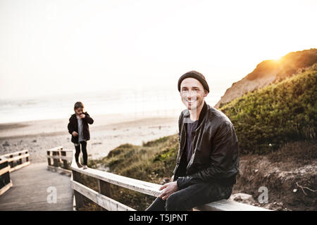 Portrait of smiling man with daughter on boardwalk près de la plage Banque D'Images