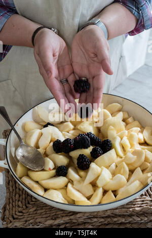 High angle portrait de personne qui met les pommes et les framboises dans un moule rond. Banque D'Images