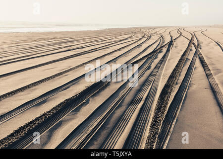 Les traces de pneus sur la surface douce de sable sur une plage. Banque D'Images