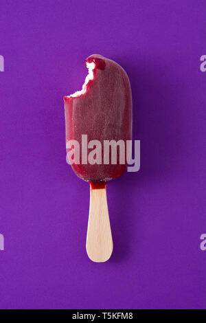 Mordu de popsicle fraise sur fond violet. Vue d'en haut Banque D'Images