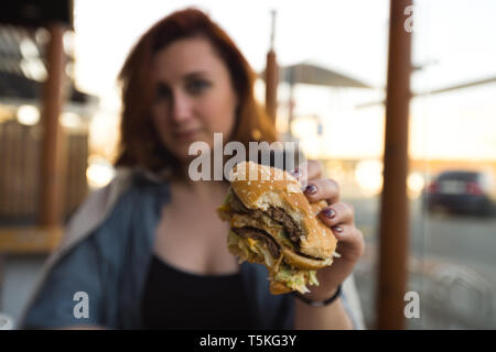 Hamburger close up - Young Woman eating dans Fast Food Restaurant - Cheeseburger, frites et soda moyen Banque D'Images