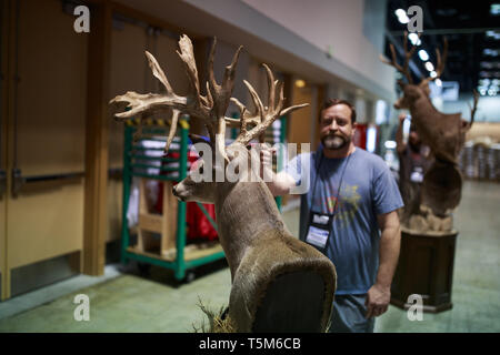 Indianapolis, Indiana, USA. Apr 25, 2019. Les travailleurs d'un chevreuil en peluche tout en mettant en place pour l'anr convention. Préparer les vendeurs de cabines dans la salle d'exposition avant de la National Rifle Association (NRA) convention à l'Indiana Convention Center dans le centre-ville d'Indianapolis. Crédit : Jeremy Hogan/SOPA Images/ZUMA/Alamy Fil Live News Banque D'Images