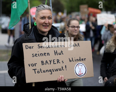 Bonn, Allemagne. Apr 26, 2019. Sur son chemin à l'Assemblée générale des actionnaires de Bayer, un participant à la 'future' vendredi pour circulation détient un panneau disant 'La Grande Faucheuse enlève son chapeau pour Bayer's blind rage de tuer. De nombreuses associations et initiatives ont protesté contre la politique d'entreprise de l'agrochimique et les compagnies pharmaceutiques. Credit : Oliver Berg/dpa/Alamy Live News Banque D'Images