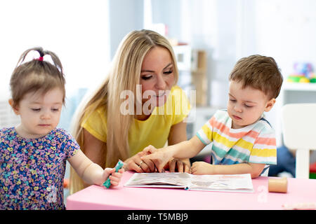 Garderie avec des enfants Les enfants de lire un livre dans le jardin d'enfants Banque D'Images