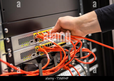 Close-up of Male Technician de brancher le câble réseau au routeur du réseau Banque D'Images