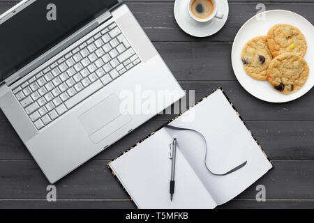 Les voisins musicaux de travail avec ordinateur portable, café, biscuits et notes sur un fond de bois foncé Banque D'Images