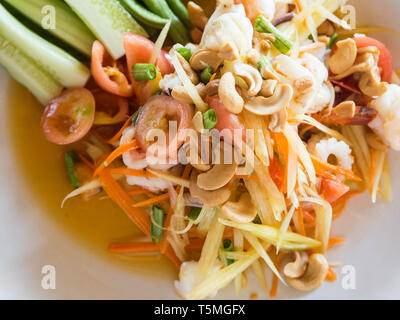 Salade traditionnelle authentique avec la papaye verte, des légumes frais et des herbes, des fruits de mer sur plaque blanche dans un restaurant thaïlandais Banque D'Images