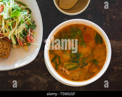 L'aigreur et épicée soupe Tom Yum Goong salade de mangue verte et poisson pané et sur la plaque sur une table dans un restaurant. La cuisine traditionnelle thaïe authentique. à Banque D'Images