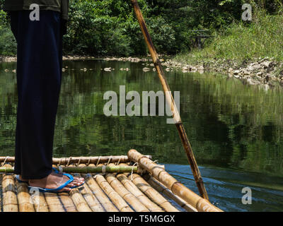 Undefined homme conduit un radeau de fortune naviguer le long d'une rivière dans la jungle Banque D'Images