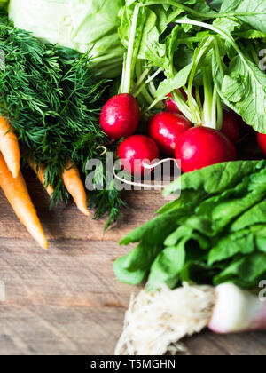 Printemps frais Légumes et fines herbes - carottes, ramson, radis, aneth, l'ail, le chou sur un fond de bois. Chasse printanière de légumes frais. Banque D'Images