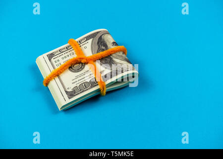 Dollar bills pliée en deux sur fond bleu clair Banque D'Images