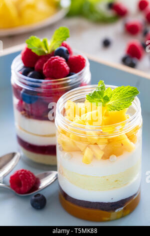 Mangue et framboise dessert, gâteau au fromage, bagatelle, la souris dans un bocal en verre sur un fond de bois, composition verticale Banque D'Images