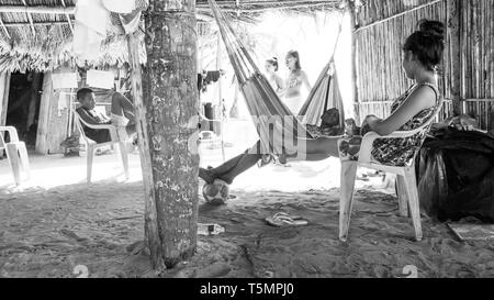 Guna (Kuna) membres de la tribu se détendre sous une grande hutte commune faite de feuilles de palmier, en regardant les touristes visiter leur île et d'acheter des molas Banque D'Images