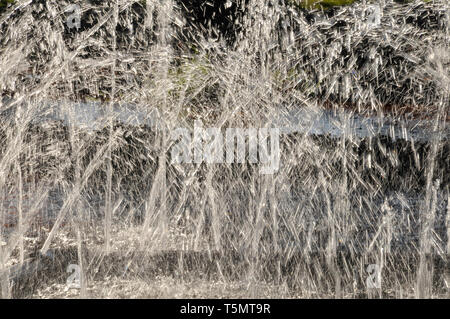 Un gros plan sur rétroéclairé de la pulvérisation des jets d'eau qui se croisent dans une fontaine. Banque D'Images