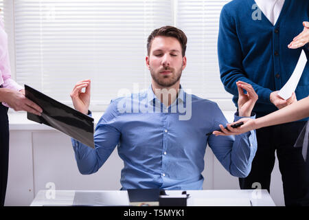 Young Businessman Meditating tandis qu'entouré par ses dirigeants Banque D'Images