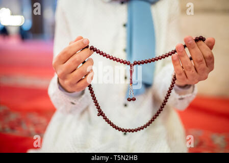 Vue rapprochée d'une femme musulmane dans les mains tout en maintenant l'hijab chapelet avec ses mains et en priant.Religion priant concept. Banque D'Images