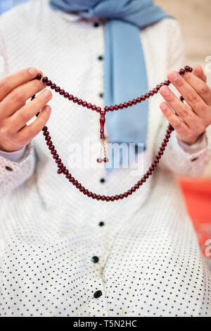 Vue rapprochée d'une femme musulmane dans les mains tout en maintenant l'hijab chapelet avec ses mains et en priant.Religion priant concept. Banque D'Images