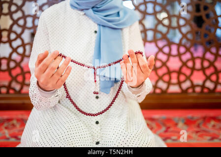 Vue rapprochée d'une femme musulmane dans les mains tout en maintenant l'hijab chapelet avec ses mains et en priant.Religion priant concept. Banque D'Images