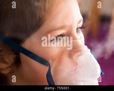 Petite fille de race blanche avec masque à oxygène en inhalation close up Banque D'Images