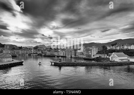 Moody Noir et blanc photo d'Un petit bateau à voile entrant dans le port pittoresque de Ålesund, Møre og Romsdal, Norvège. Banque D'Images