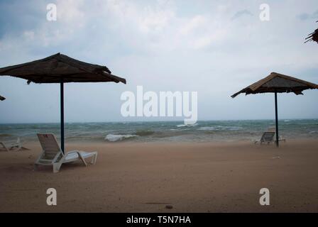 Tempête sur la mer avec des nuages orageux. Parasols et transats sur la plage Banque D'Images