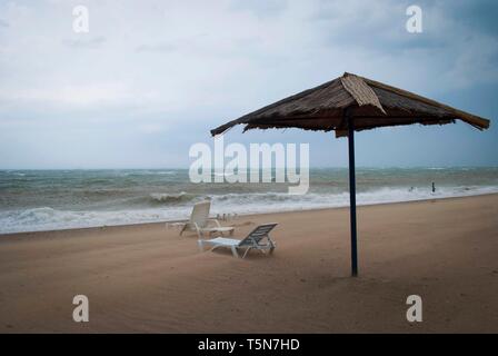 Tempête sur la mer avec des nuages orageux. Parasol et chaises longues sur la plage Banque D'Images