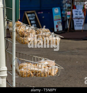 Sacs de plastique transparent contenant des aliments pour oiseaux sur fond blanc rayonnage à l'extérieur d'un magasin dans le village de Horning, Norfolk. L'alimentation des oiseaux est vendus aux touristes, h Banque D'Images
