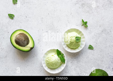 La crème glacée à l'avocat de pierre blanche sur arrière-plan, Vue de dessus, copiez l'espace. Vegan vert avocat biologique ou la crème glacée gelato pistache avec des feuilles de menthe. Banque D'Images