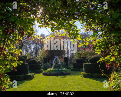 Le jardin blanc et la sculpture à Chenies Manor, Buckinghamshire en avril soleil belle pelouse verte fraîche, encadrées de akebia, chocolat de vigne. Banque D'Images