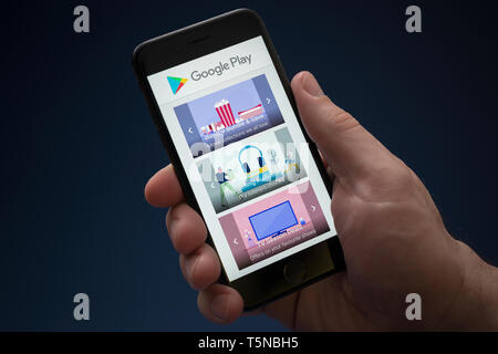 Un homme se penche sur son iPhone qui affiche le logo Google Play (usage éditorial uniquement). Banque D'Images
