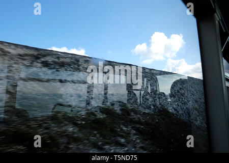 Silhouette reflet dans un fenêtre de l'autobus d'un bus de passagers et de l'intérieur par la fenêtre pour voir l'horizon de mer avec ciel bleu et les nuages blancs au-delà. Banque D'Images