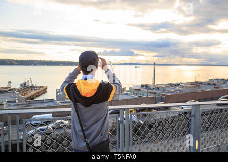 Un visiteur au pont d'observation du marché de Pike Place à prendre des photos de coucher de soleil avec l'horizon de Puget Sound. son téléphone mobile. Seattle, USA. Banque D'Images