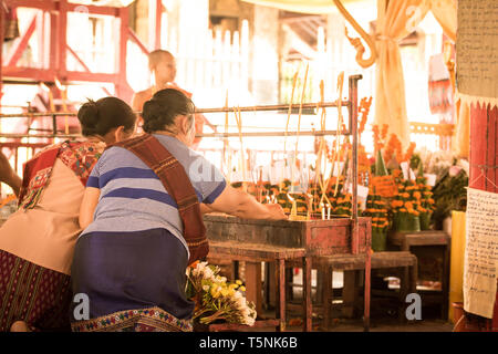 Deux femmes éclairant des bougies à Wat Xieng Thong, Luang Prabang, pendant le lavage du bouddha, le nouvel an lao. Banque D'Images