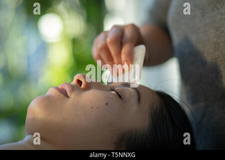 Young woman receiving gua sha rajeunissement du visage traitement avec le quartz rose en acupuncture spa Wellness Clinic Banque D'Images